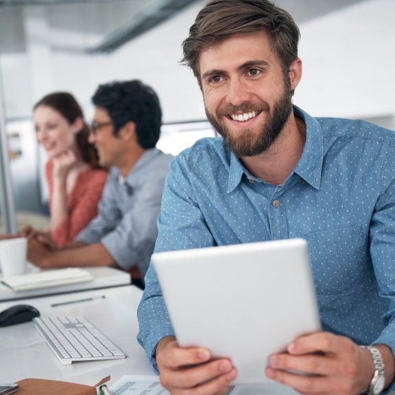 Lächelnder Mann sitzt und hält Tabletcomputer in der Hand