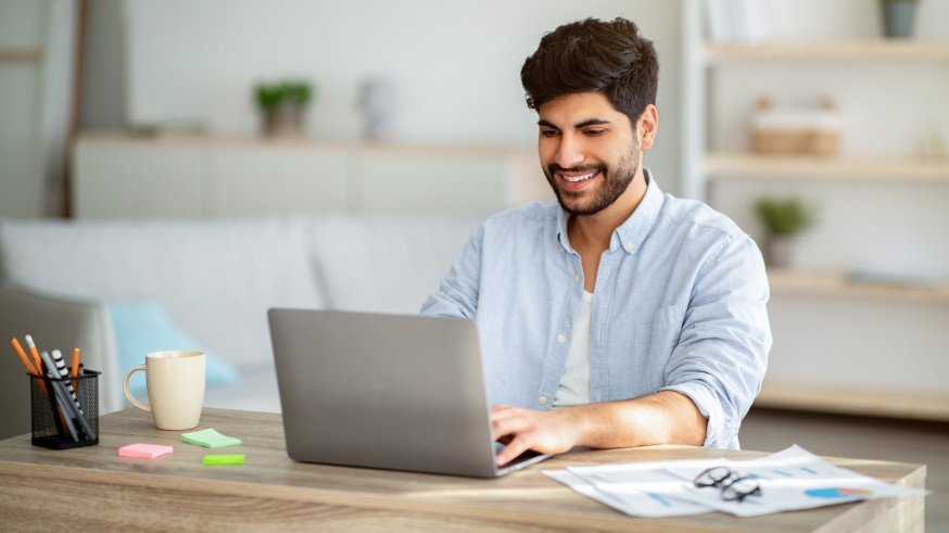 Bärtiger Mann lächelt Laptop an