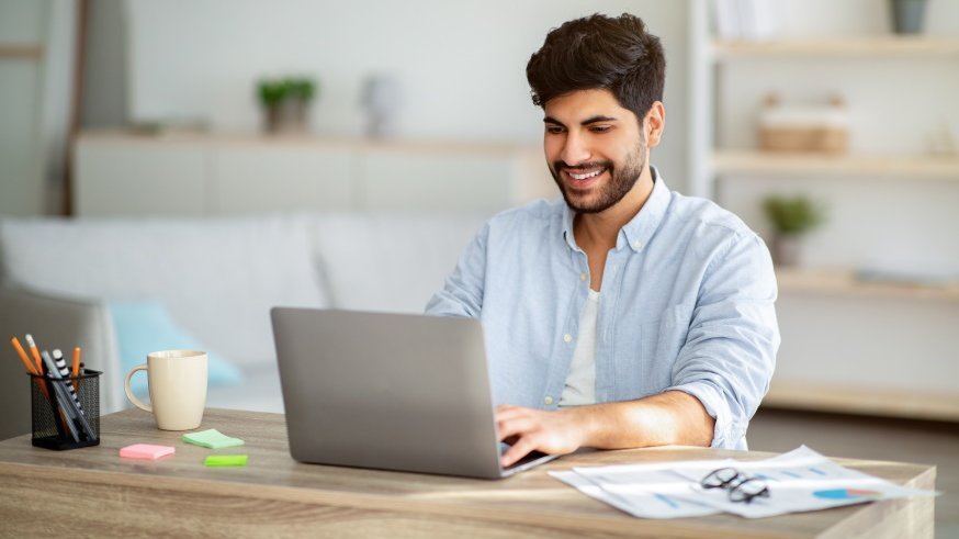 Bärtiger Mann lächelt Laptop an