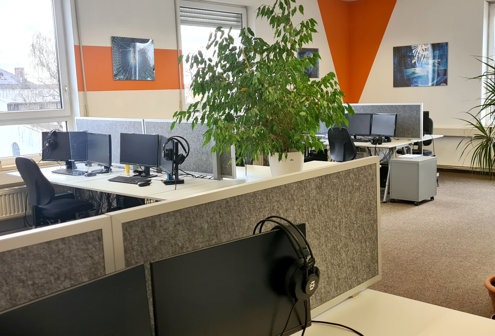 Modernes Büro mit Sichtschutz, Monitoren und Kopfhörern