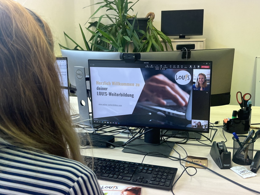 Betrachter neben Frau blickt in Laptop mit LOUIS-Präsentation in Microsoft Teams