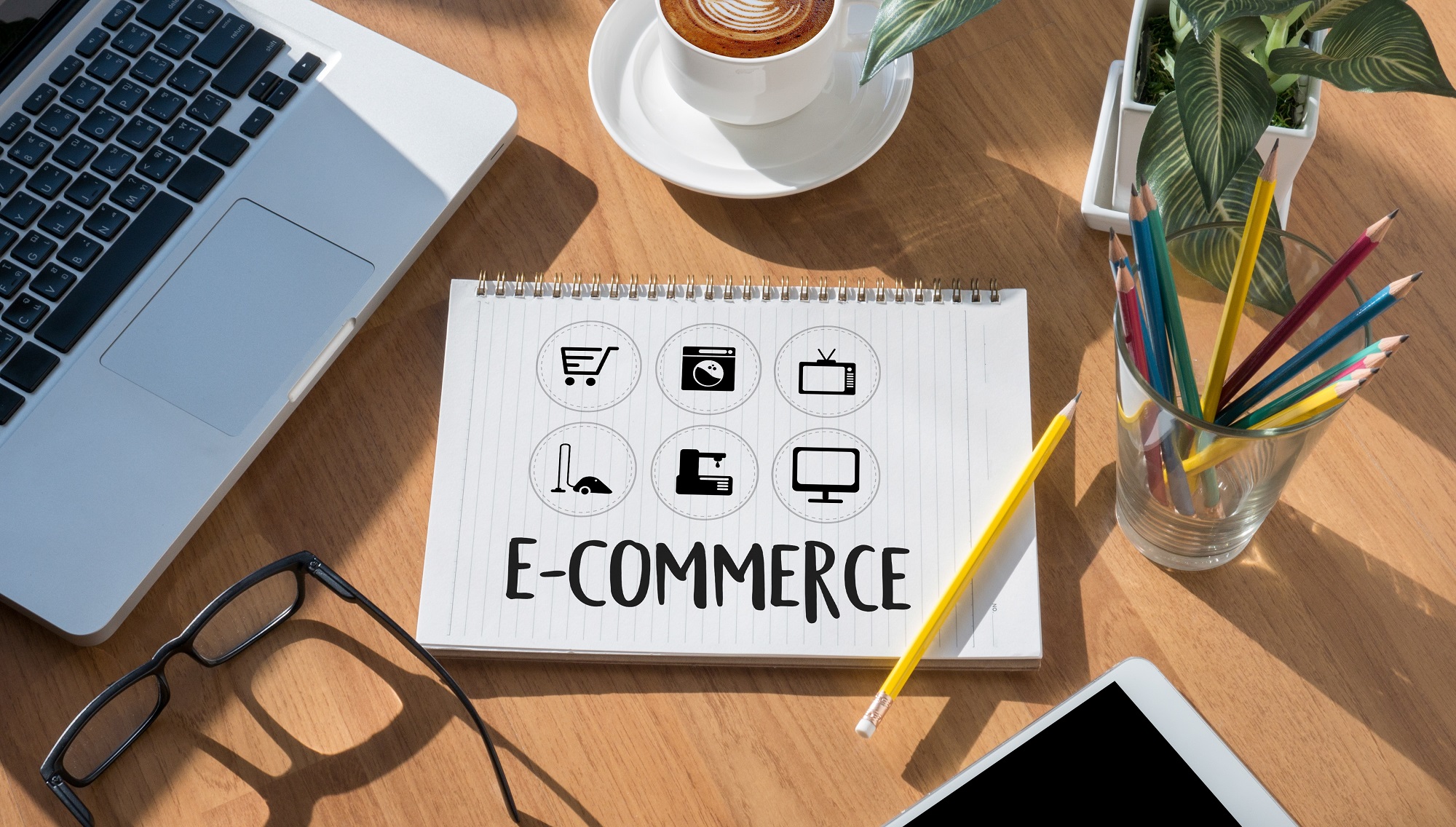 Schreibblock neben Laptop mit Text "E-Commerce"