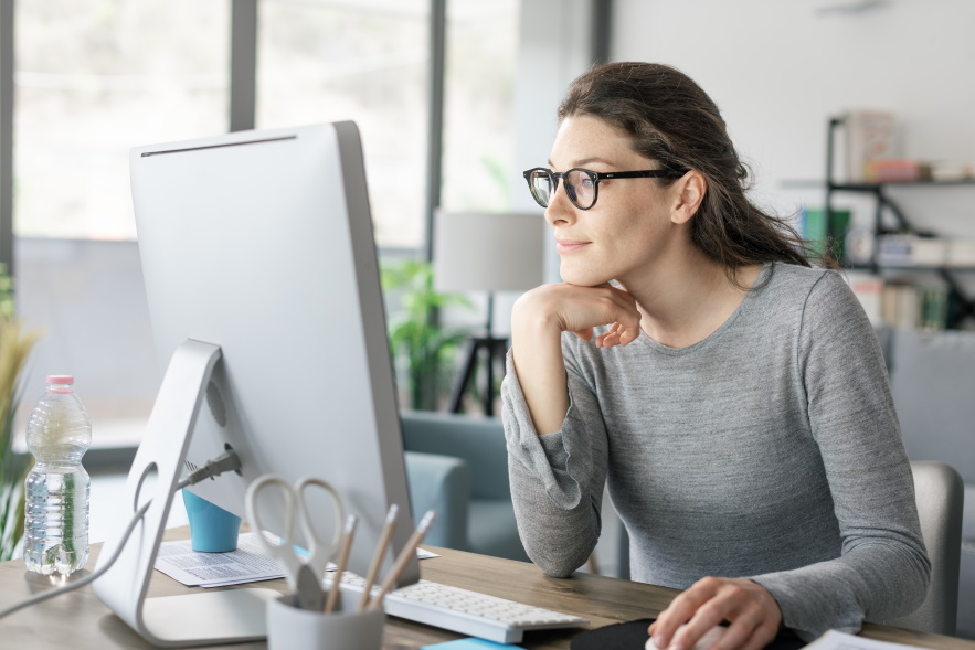 Bebrillte Frau schaut konzentriert in den Monitor