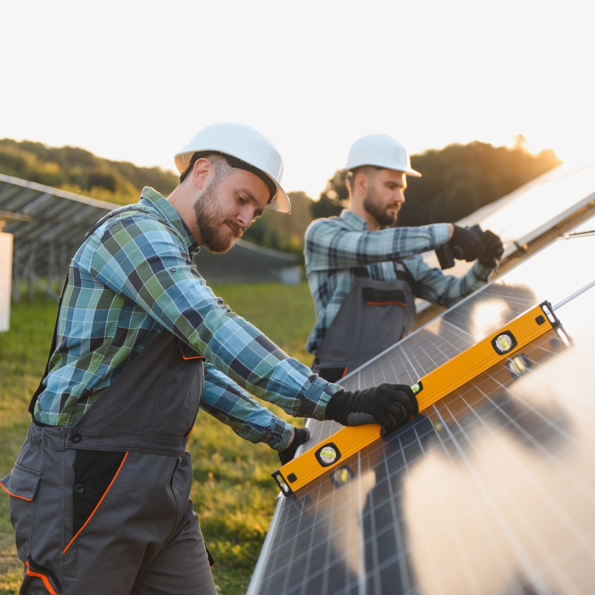 Zwei Männer mit Helm und Handwerkerkleidung arbeiten an einer Solaranlage.