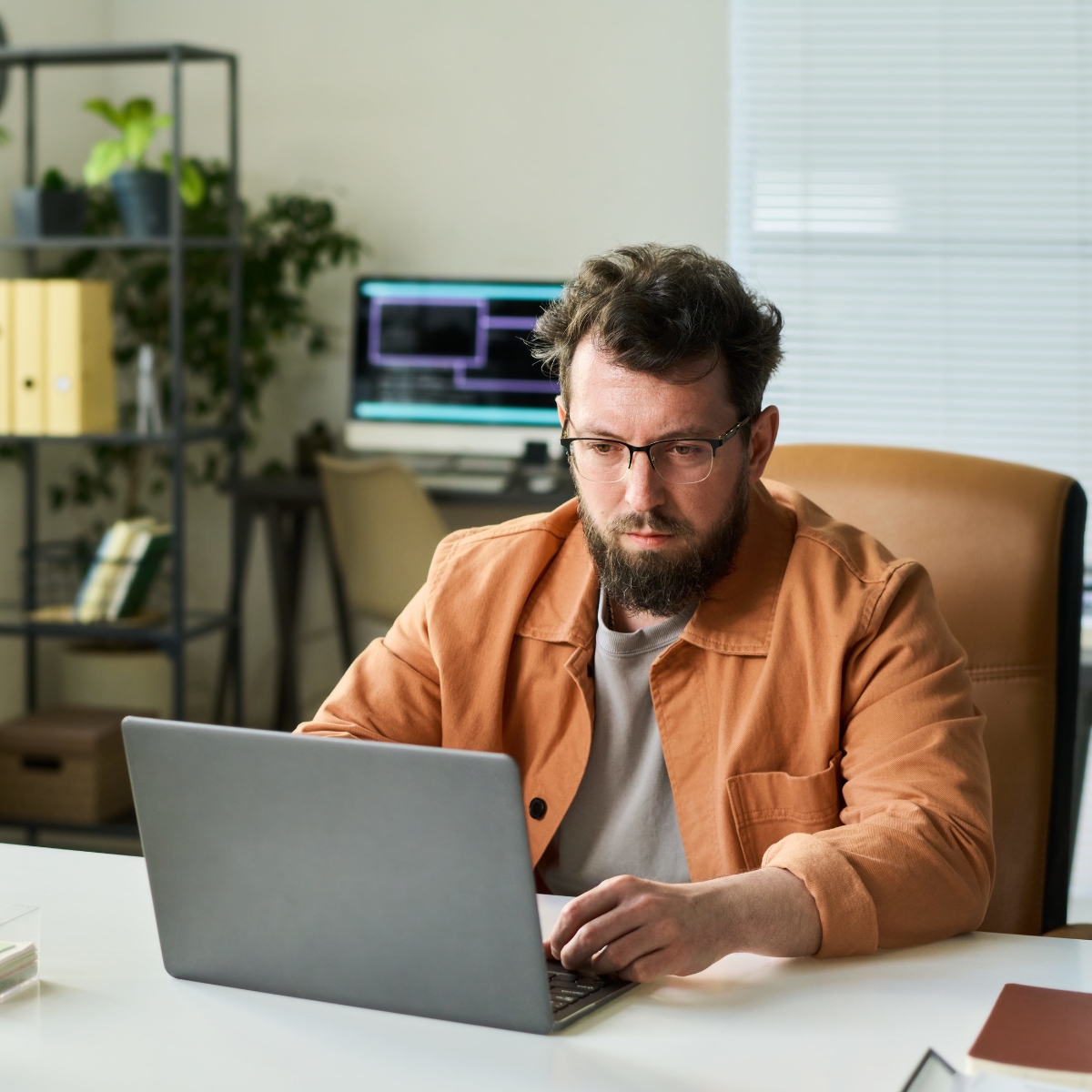 Ein Mann mit Bart und Brille arbeitet am Laptop.