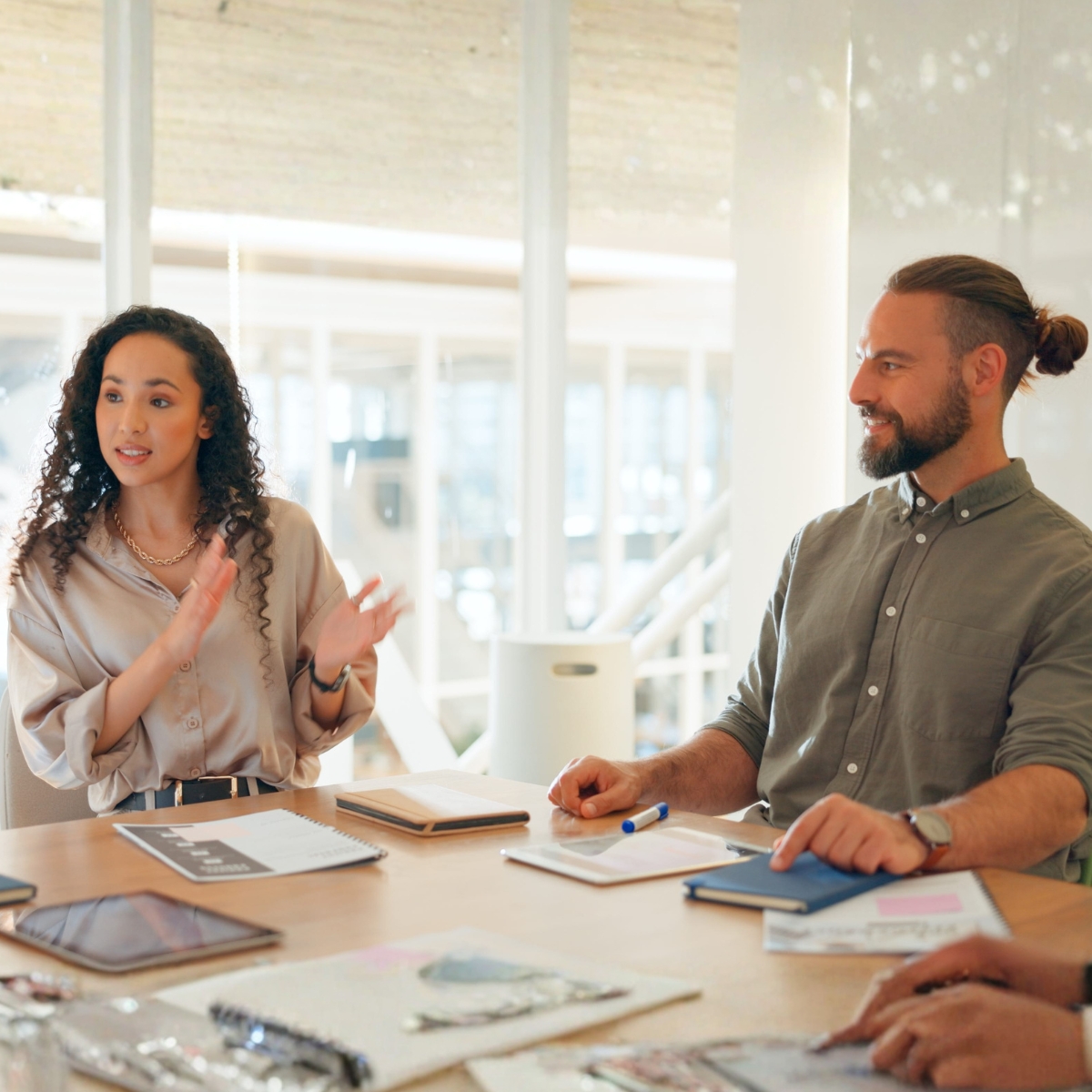 Eine Frau und ein Mann sitzen an einem Konferenztisch. Die Frau spricht und gestikuliert. Der Mann sieht sie an.